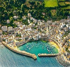 an aerial view of a small town on the water's edge with boats in it