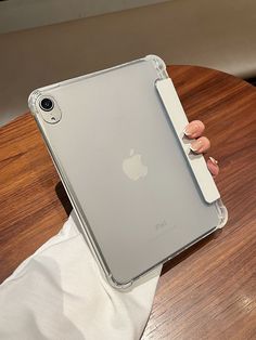 a person holding an ipad on top of a wooden table with a white mouse in their hand