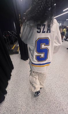 a young child wearing a hockey jersey walking through an airport terminal with his back turned to the camera