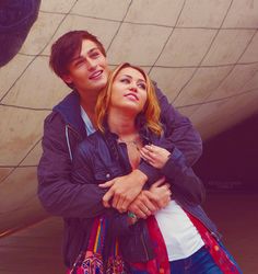 a man and woman standing next to each other in front of a large ball sculpture