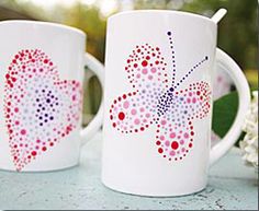 two white coffee mugs decorated with red and blue polka dot butterfly designs on them