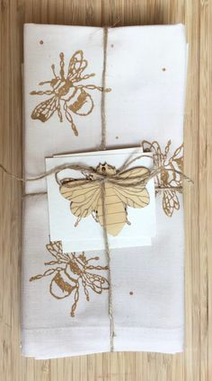 two napkins tied up with twine on top of each other in front of a wooden table