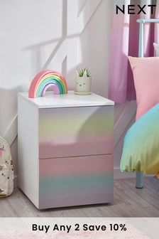 a white nightstand with a rainbow design on the top and pink rugs next to it