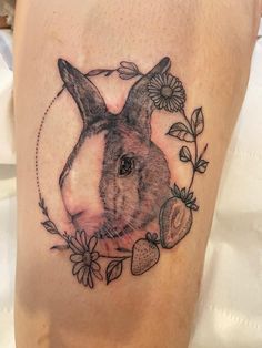 a rabbit with flowers and leaves around it's head on the side of a woman's thigh