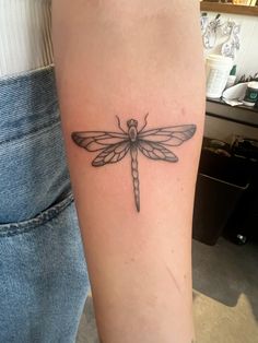 a small dragonfly tattoo on the arm