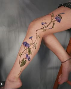 a woman's legs with tattoos on them and flowers growing out of the leg