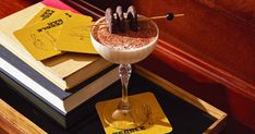 a drink sitting on top of a wooden table next to a stack of yellow cards