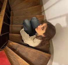 a woman sitting on top of a wooden staircase