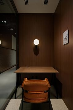 a brown chair sitting in front of a table with a lamp on top of it