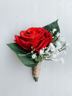 a bouquet of red roses and white flowers is tied to a piece of jute