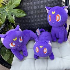 three purple stuffed animals sitting on top of a white cushion in front of a chair