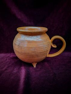 a brown vase sitting on top of a purple cloth