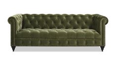 a green velvet couch with studding on the arms and back, in front of a white background