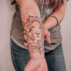 a woman's arm with a lion and flowers tattoo on her left hand,