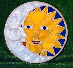 a ceramic sun and moon on green grass