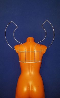 an orange plastic mannequin with metal wire around it's neck and back