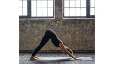 a woman is doing yoga in front of two windows with her hands on the ground