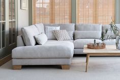 a living room with a couch, coffee table and window blinds on the windowsill