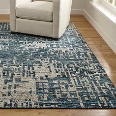 a chair sitting on top of a wooden floor in front of a large blue rug