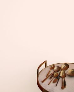 spoons and utensils sit on a table against a pink background with gold accents