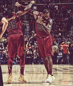 two men in maroon uniforms standing on a basketball court with their arms around each other