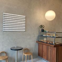 two stools in front of a counter with pastries on it and a light fixture hanging from the ceiling