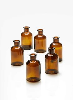 six brown glass bottles sitting on top of a white table