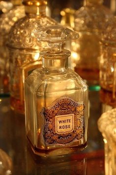 a bottle of white rose perfume sitting on top of a table next to other bottles