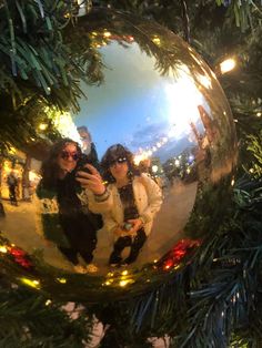 two women are taking a selfie in a christmas ornament on a tree