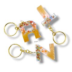 three key chains with letters made out of glass and gold platings on them