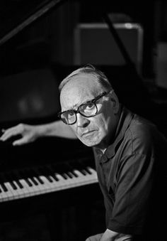 a man in glasses is sitting at a piano