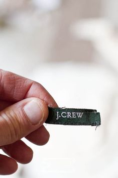 a hand holding a small piece of cloth with the word screw written on it