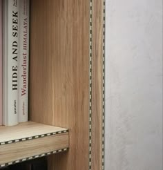 two books are sitting on top of each other in a book shelf next to a wall