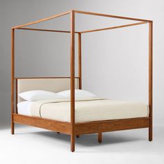 a four poster bed with white sheets and pillows on the headboard is made from wood