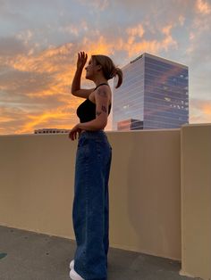 a woman standing on top of a roof next to a tall building