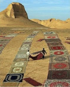 two men working on rugs in the desert