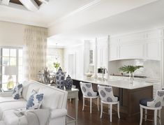 a living room filled with furniture next to a kitchen and dining room table covered in blue and white pillows