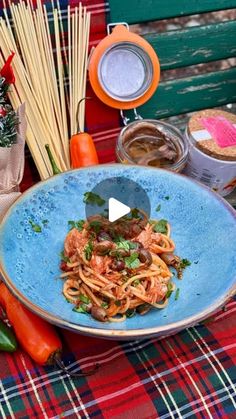 a blue plate topped with pasta and vegetables on top of a table next to other foods