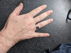 a man's hand with a ring on it next to some sunglasses and a pair of glasses