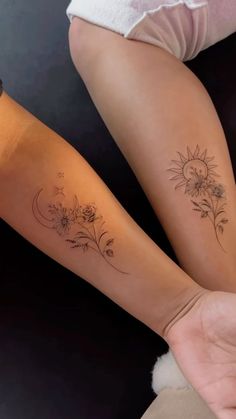 two women with matching tattoos on their arms, one is holding the other's hand