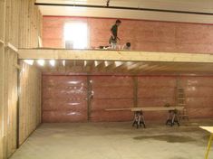 a man is standing on top of a ladder in an unfinished room with pink walls