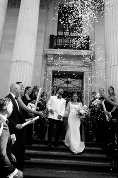 the bride and groom are walking down the stairs with confetti