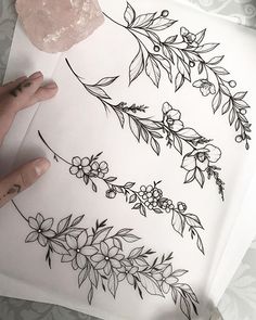 someone is drawing flowers and leaves on a piece of paper