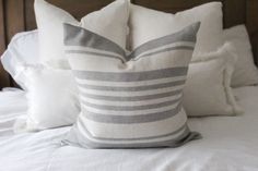 a bed with white and gray pillows on top of it