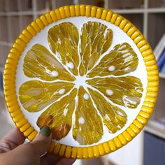 a hand holding a yellow and white plate with orange slices on it