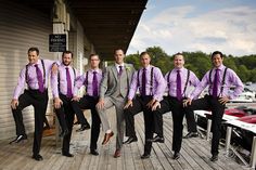 a group of men in suits and ties posing for a photo on a dock with their legs crossed