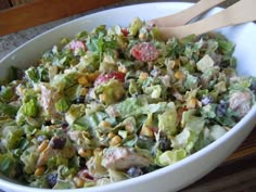 a white bowl filled with salad sitting on top of a table next to a bag of chips