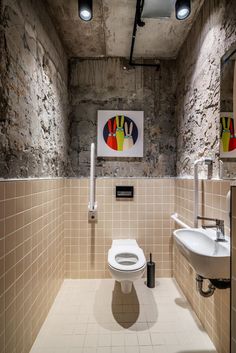 a bathroom with two sinks, a toilet and a painting on the wall above it