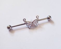 a butterfly shaped barbell ring with two balls on it