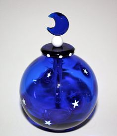 a blue glass vase with white stars and a crescent on it's top sitting on a table